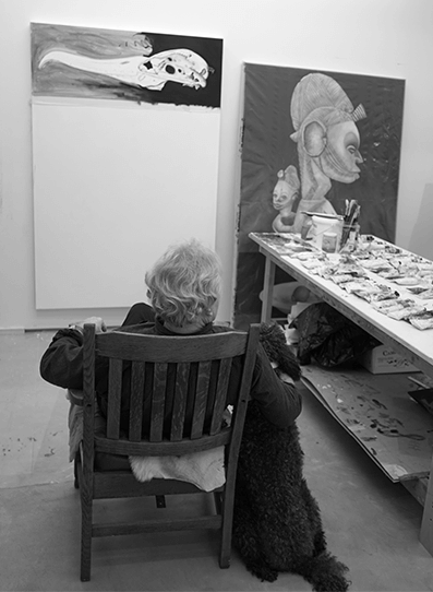 artist sitting in chair facing painting - art table on right